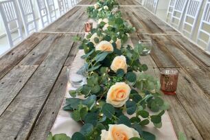 Rose garland centrepieces on long wooden tables