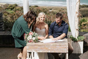 A happy bride & groom signing the registry at a beachside wedding