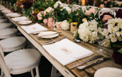 Image shows a long wooden table set for a rustic style wedding