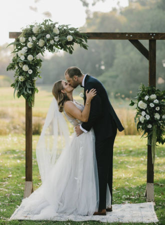 Bride and Groom kissing under a timber arbour