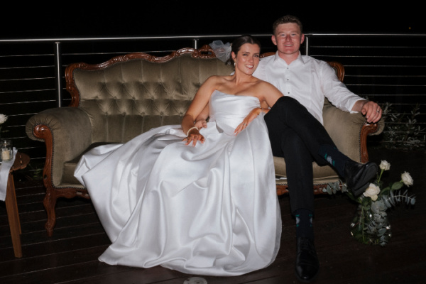 Smiling bride and groom lounging on a vintage sofa
