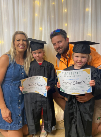 A family posing in front of a fairy light backdrop for kinder graduation