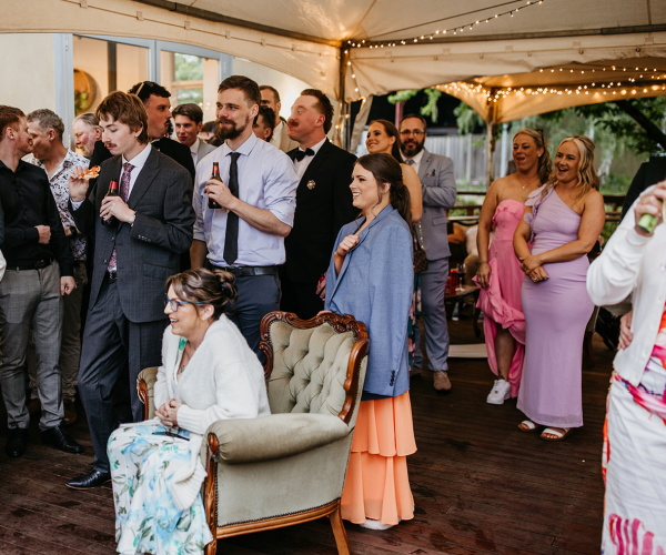 Engagement party guests listening to speeches under a fairy lit marquee
