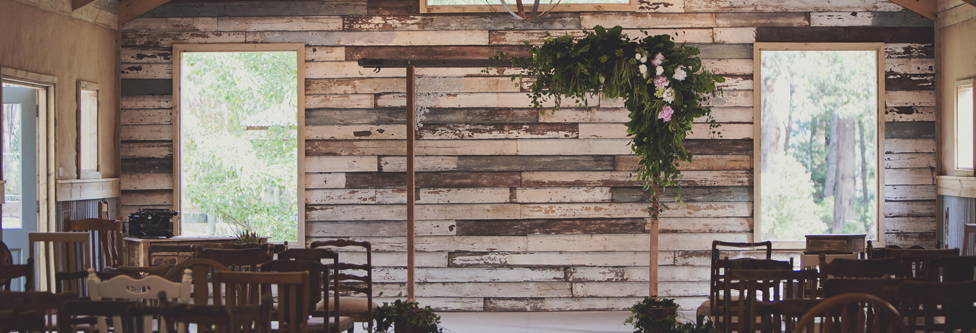 Rustic wedding ceremony setup in barn with wooden arbour