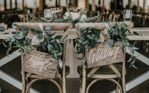 Photo shows Rustic Bride and Groom chair signs with native greenery