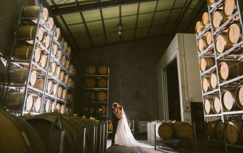Photo shows a bride and groom inside the barrel room at Vines of the Yarra Valley